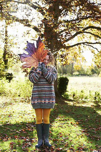 Mädchen beim Spielen mit Herbstlaub im Freien