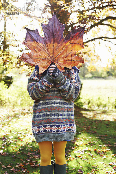 Mädchen beim Spielen mit Herbstlaub im Freien