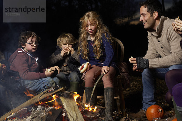 Familienessen am Lagerfeuer bei Nacht