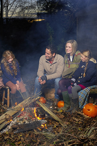 Familie entspannt am Lagerfeuer bei Nacht