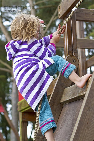 Mädchen klettert auf einem Spielplatz