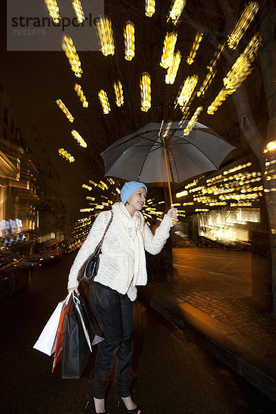 Frau unter dem Regenschirm auf der Stadtstraße