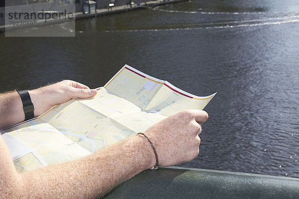 Mann liest Stadtplan auf Brücke