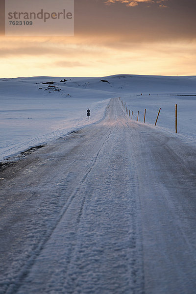 Gefrorene Straße in verschneiter Landschaft