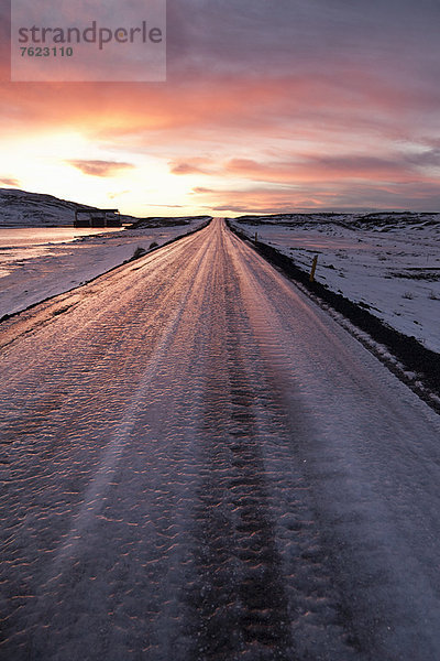 Gefrorene Straße in verschneiter Landschaft