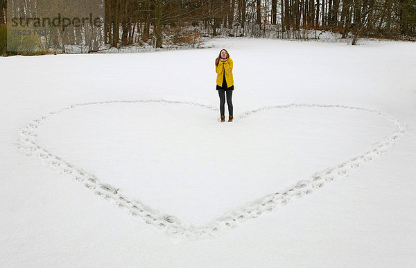 Frau  die das Herz im Schnee formt