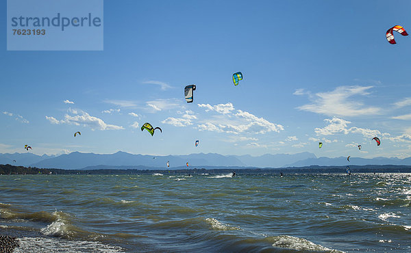 Segel von Kitesurfern über Kabbelwellen