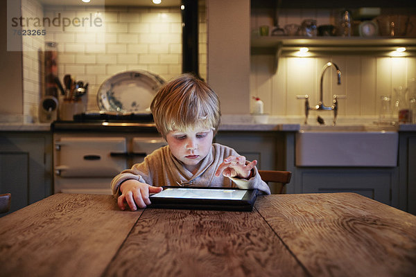 Junge mit Tablet-Computer am Tisch