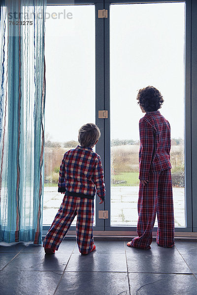Jungen im Pyjama  die aus dem Fenster schauen