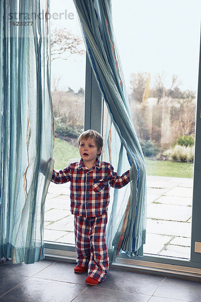 Junge im Pyjama spielt im Vorhang