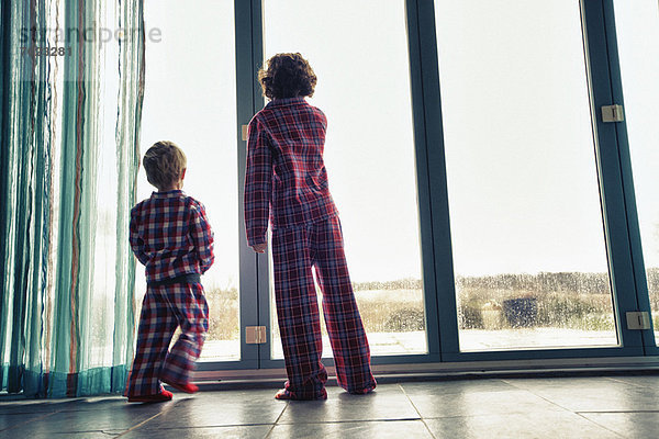 Jungen im Pyjama  die aus dem Fenster schauen