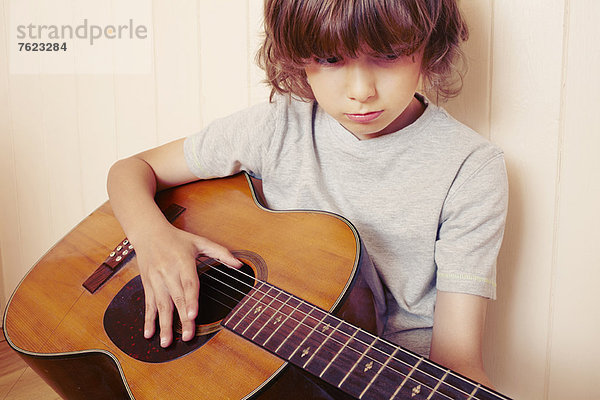 Junge spielt Gitarre im Haus