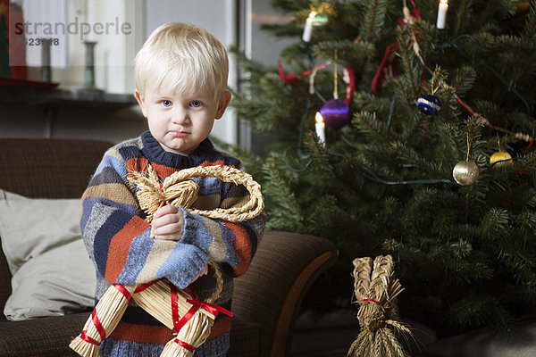 Junge mit Spielzeug am Weihnachtsbaum