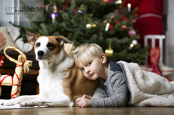Junge und Hund am Weihnachtsbaum
