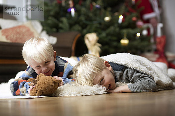 Jungen spielen auf dem Boden am Weihnachtsbaum