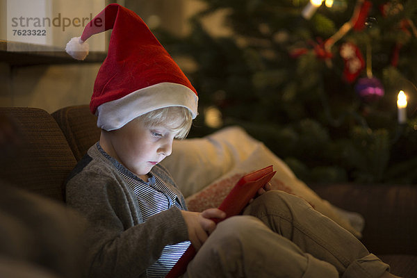 Junge mit Nikolausmütze mit Tablet-Computer