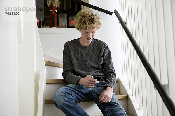 Teenager-Junge mit Handy auf der Treppe