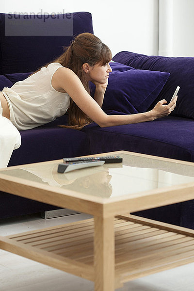 Frau fotografiert sich auf dem Sofa