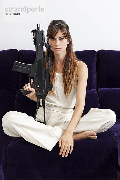 Frau mit Maschinengewehr auf Sofa