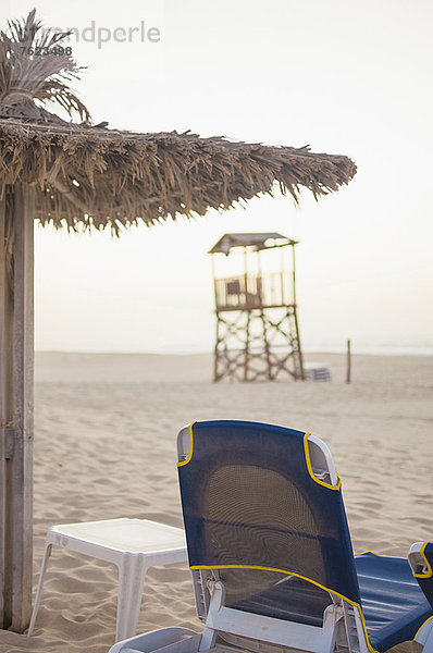 Liegestuhl und Sonnenschirm am Strand