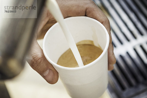 Nahaufnahme des Milchflusses in die Kaffeetasse