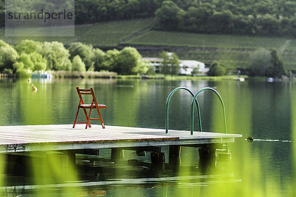 Stuhl auf hölzernem Pier im stillen See