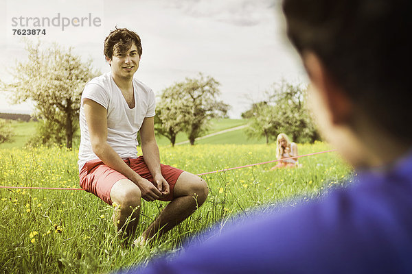 Mann auf Drahtseil im Feld sitzend