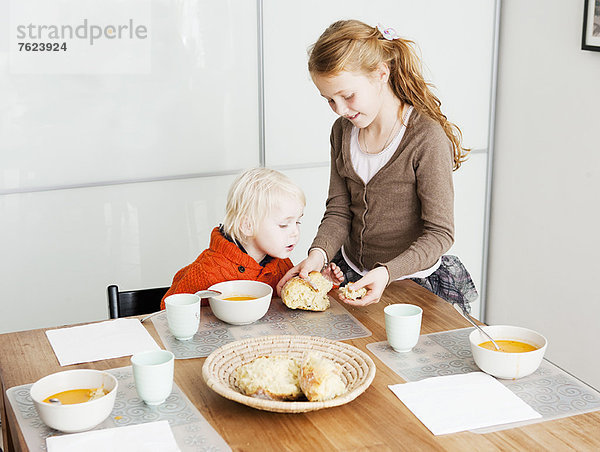 Mädchen serviert Bruder Mittagessen am Tisch