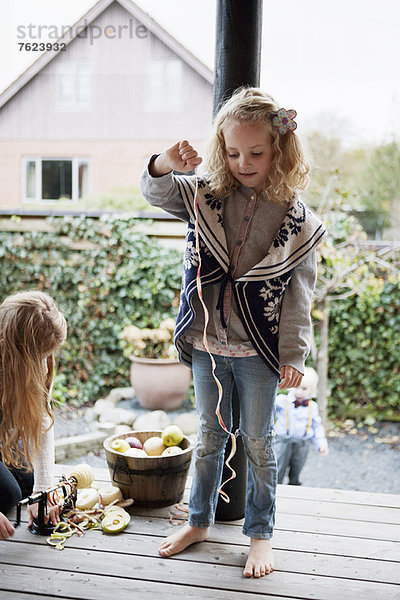 Mädchen spielt mit Fruchtschale auf der Terrasse