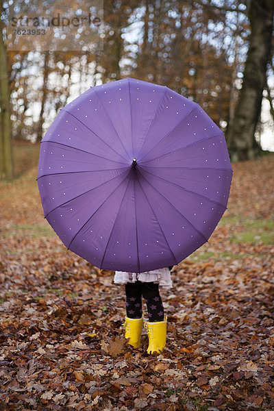 Mädchen spielt mit Regenschirm im Park