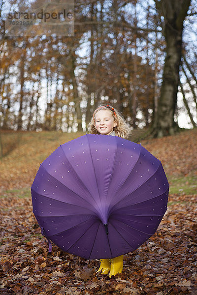 Mädchen spielt mit Regenschirm im Park