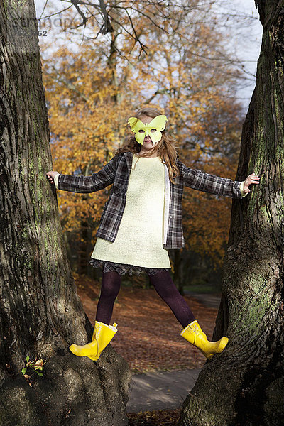 Mädchen spielt in Schmetterlingsmaske im Baum