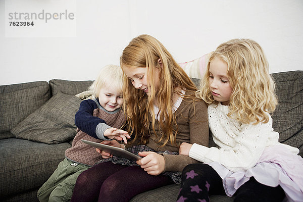 Kinder mit Tablet-Computer auf dem Sofa