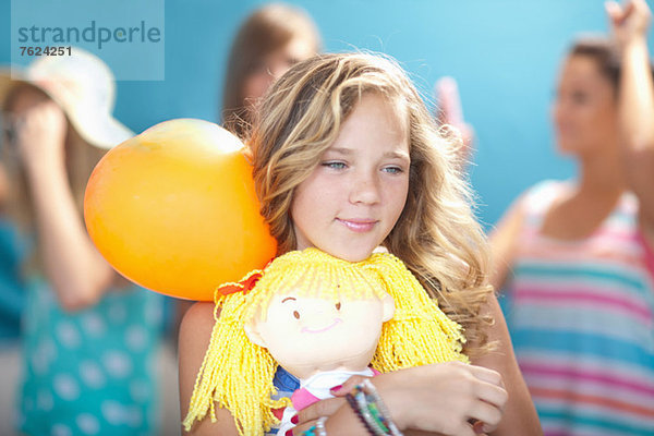 Lächelndes Mädchen mit Ballon und Puppe