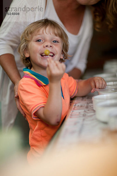 Lächelnder Junge mit Oliven im Lebensmittelgeschäft