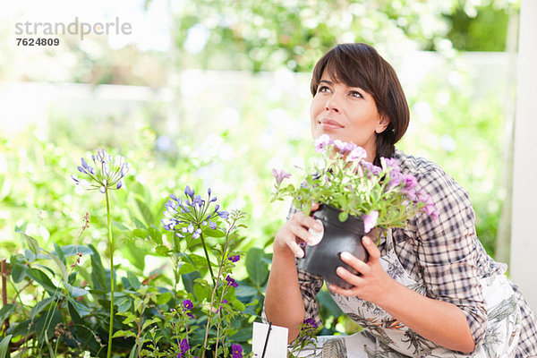 Frau mit Topfpflanze im Garten