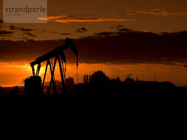 Silhouette der Ölquelle bei Sonnenuntergang