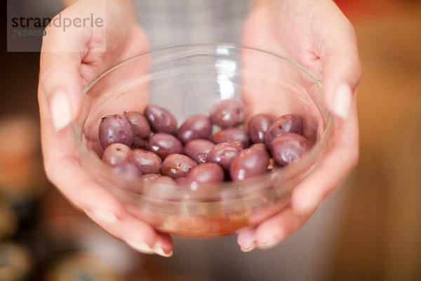 Frau hält Schale mit Oliven im Lebensmittelgeschäft