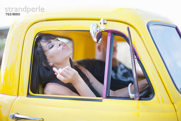 Frau beim Schminken im Autospiegel