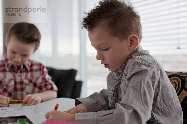 Jungen beim gemeinsamen Malen am Tisch