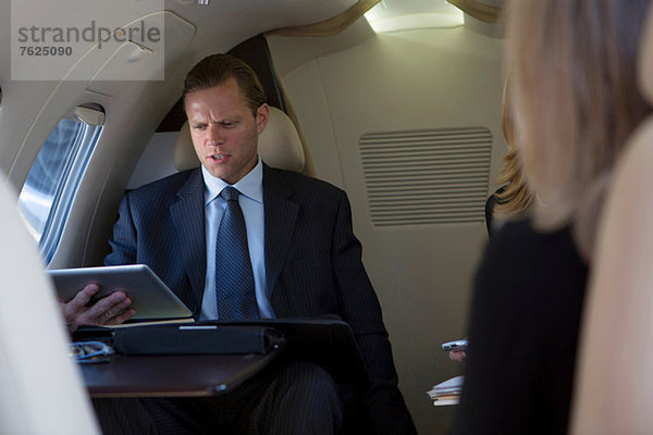 Geschäftsmann mit Tablette im Flugzeug