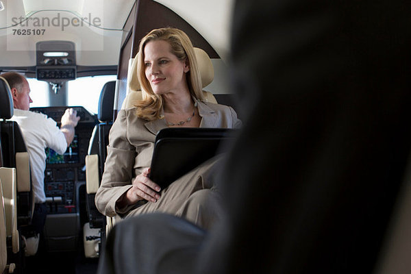 Geschäftsfrau im Flugzeug sitzend