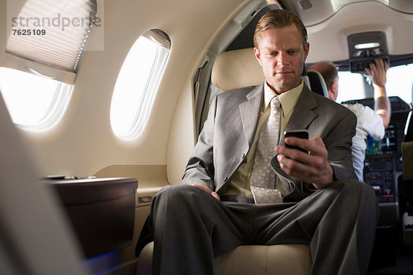 Geschäftsmann mit Handy im Flugzeug