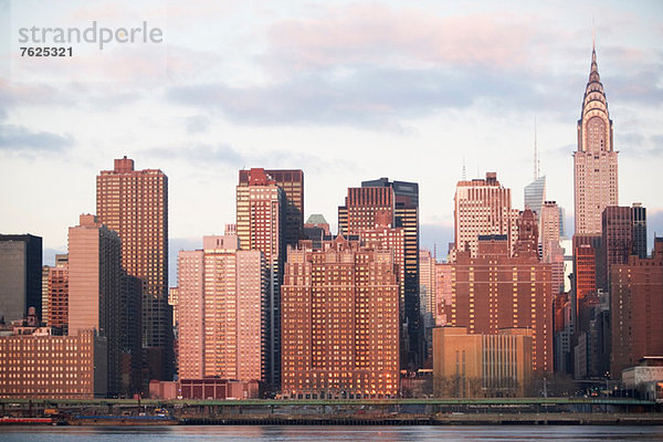Die Skyline von New York City leuchtet in der Abenddämmerung.