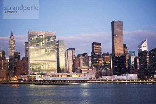 Die Skyline von New York City leuchtet in der Abenddämmerung.