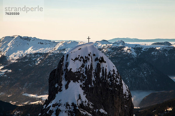 Kreuz auf verschneiter Bergspitze