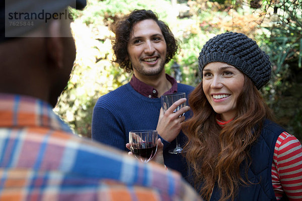 Lächelnde Freunde bei Wein im Freien