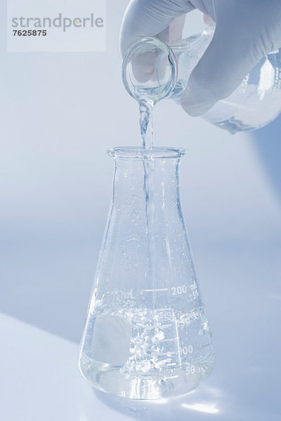 Wissenschaftler gießt Flüssigkeit in ein Becherglas