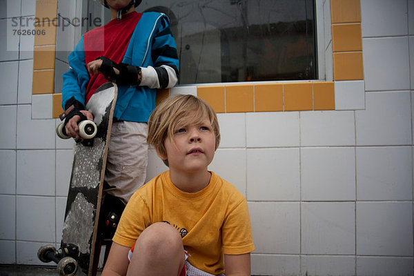 Jungen mit Skateboard im Freien sitzend