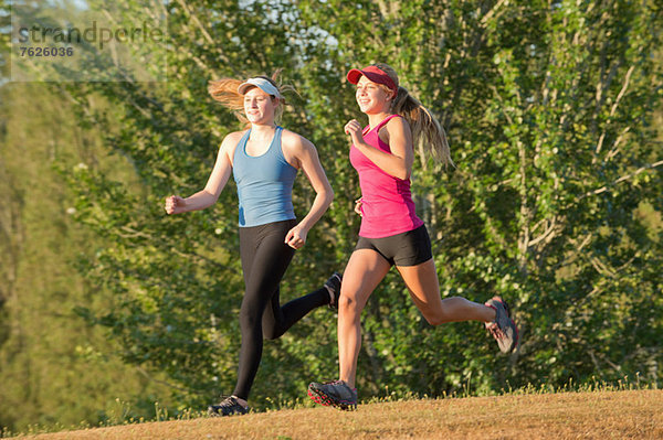 Teenager-Mädchen laufen zusammen im Feld.